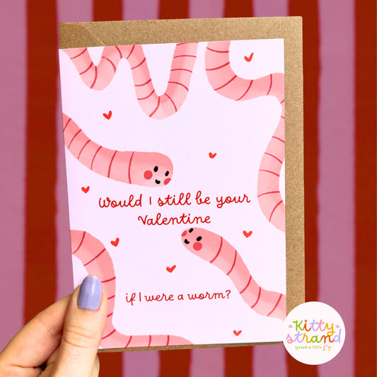 Valentine's Day card with pink worms and text held by a hand against a striped background