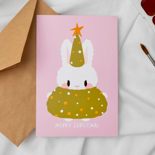 Greeting card with a festive bunny design on a pink background, accompanied by a brown envelope.
