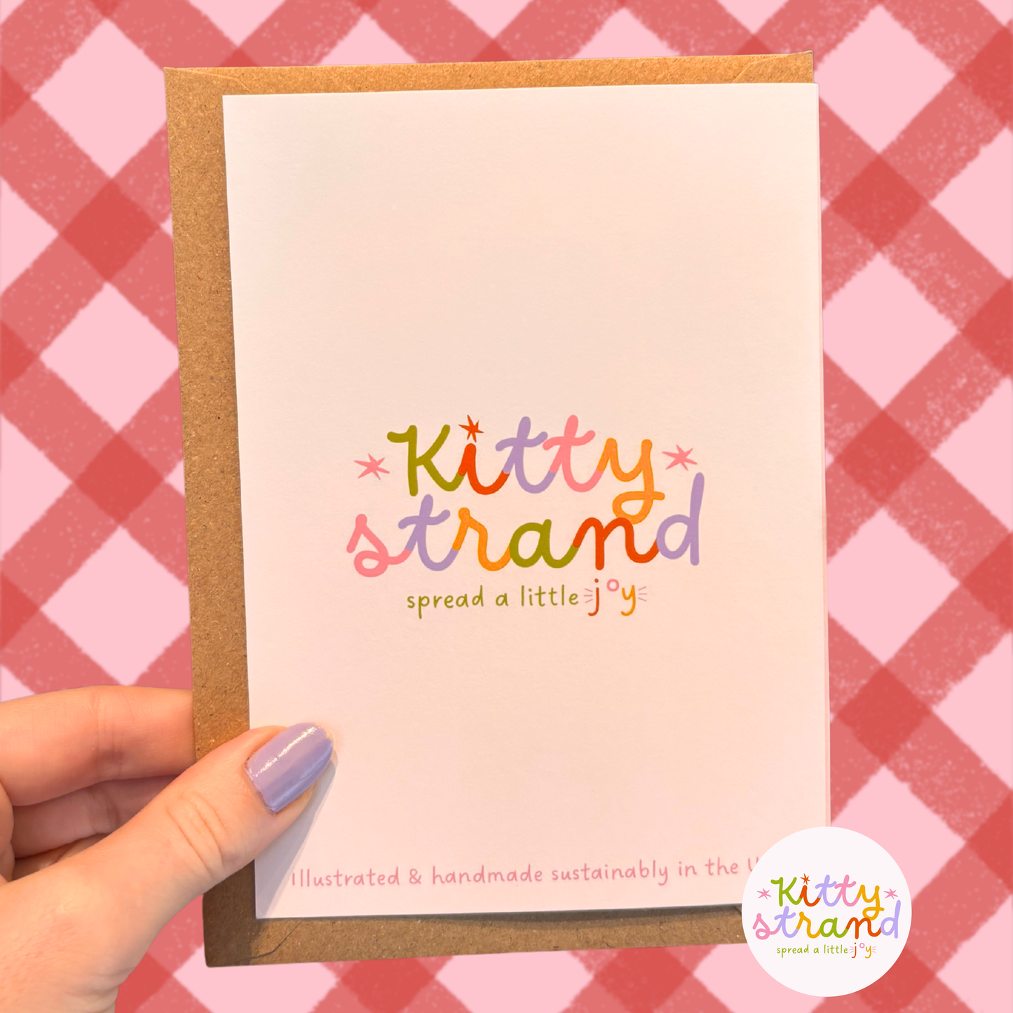 Hand holding a card with 'Kitty Strand' text against a pink and red checkered background
