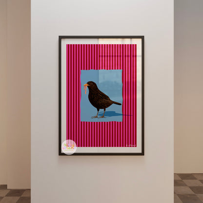 pink and blue bird-inspired wall art. Wall art with a vibrant striped pink background and a soft blue geometric square sits behind an original hand illustration of a blackbird with a worm in its mouth. Colourful, bold dopamine decor art print for nature lovers displayed in a wood frame