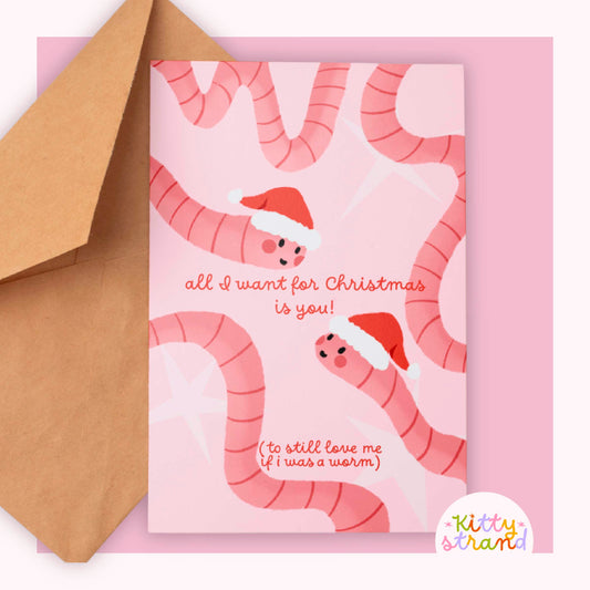 Christmas card for boyfriend with pink worms wearing Santa hats and text on a pink background. Text reads "All I want for christmas is you (to still love me if I was a worm)"