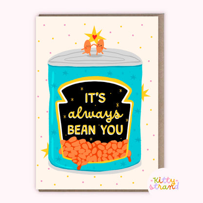 Card with a can of beans illustration and 'It's always bean you' text, held against a striped background.