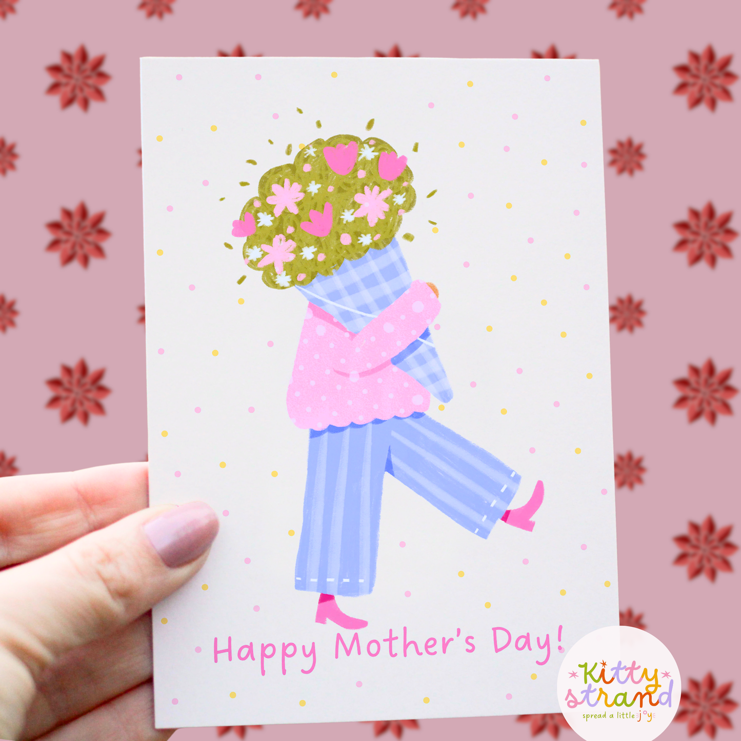 Mother's Day card with a stylized illustration of a woman holding flowers, held by a hand against a floral-patterned background.