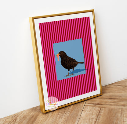 pink and blue bird-inspired wall art. Wall art with a vibrant striped pink background and a soft blue geometric square sits behind an original hand illustration of a blackbird with a worm in its mouth. Colourful, bold dopamine decor art print for nature lovers displayed in a wood frame