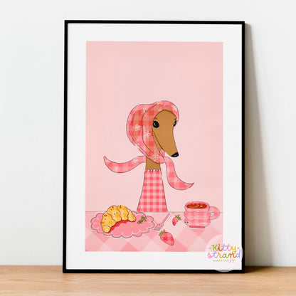 Framed artwork of a dachshund in a pink outfit with a scarf on a pink background.