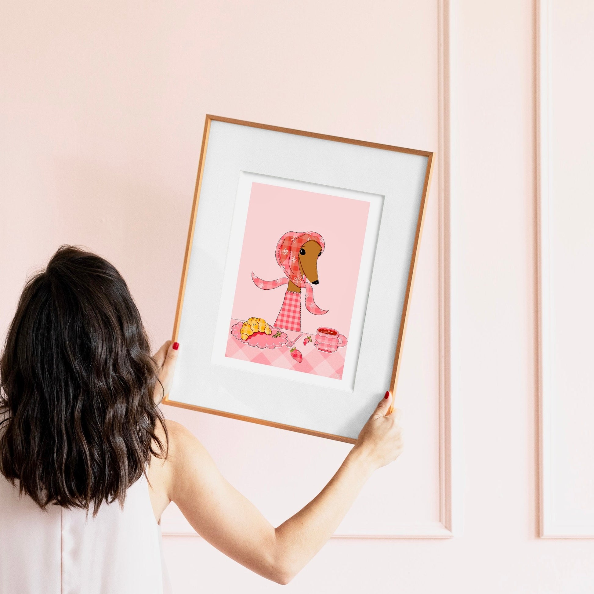 Person holding a framed illustration of a dog eating brunch 