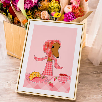 Framed illustration of a dog wearing a pink checkered outfit with a cup of coffee and croisant on a pink background, surrounded by flowers.