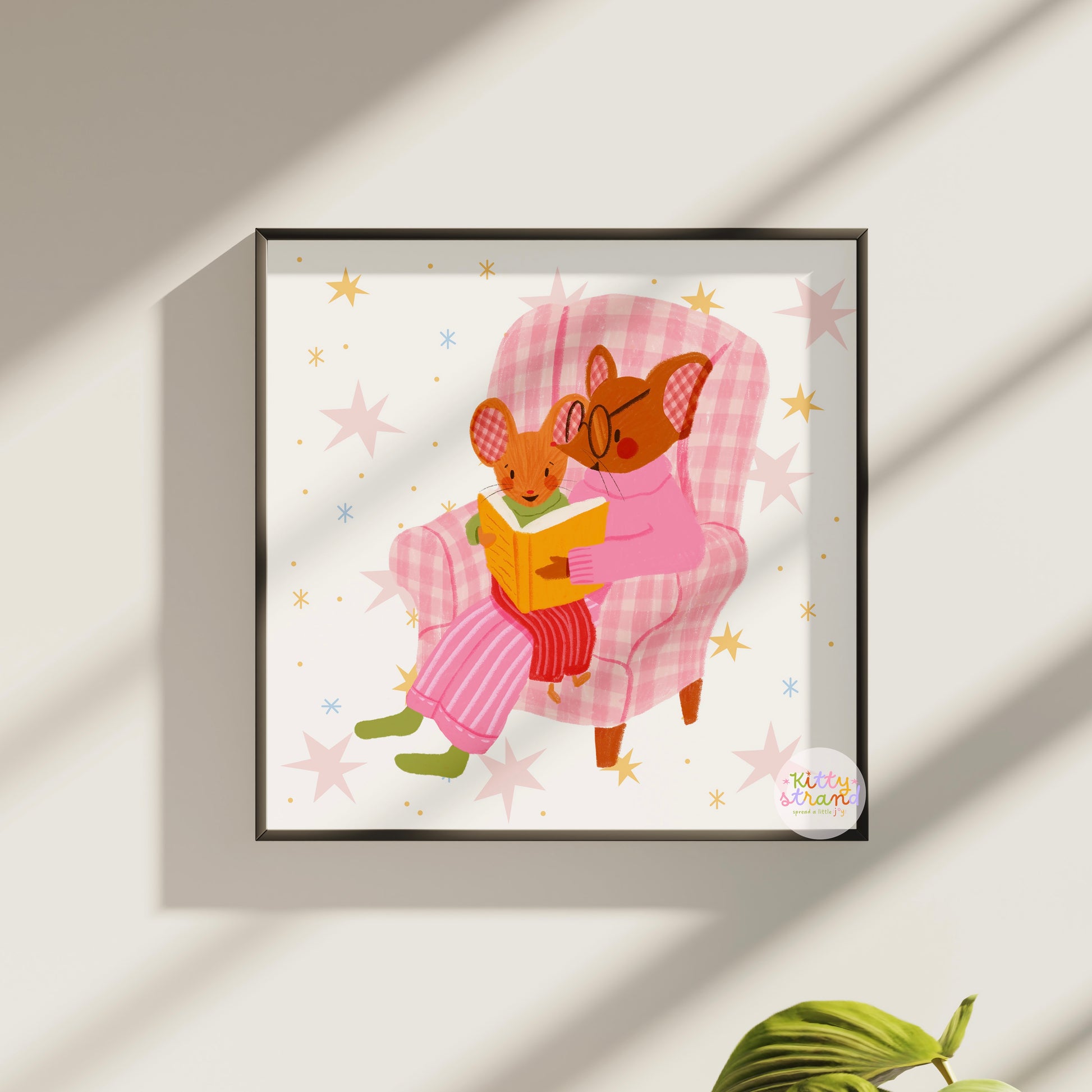wall art with an illustration of two mice reading a book in a checkered chair with a pink background. Children's book inspired wall decor