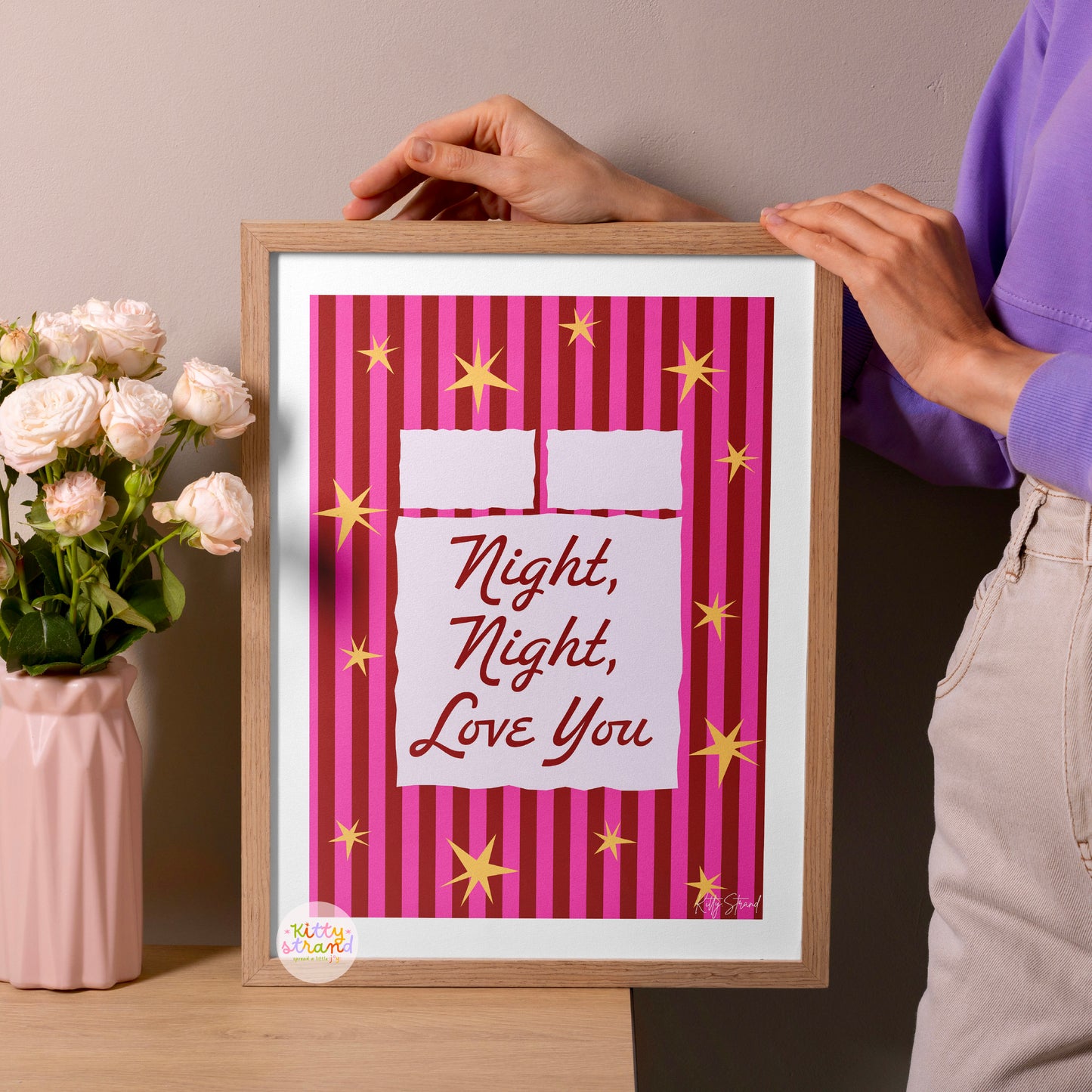 Framed artwork with 'Night, Night, Love You' text on a pink background, held by a person.