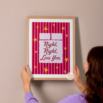 Person hanging a framed print with 'Night, Night, Love You' text on a wall.