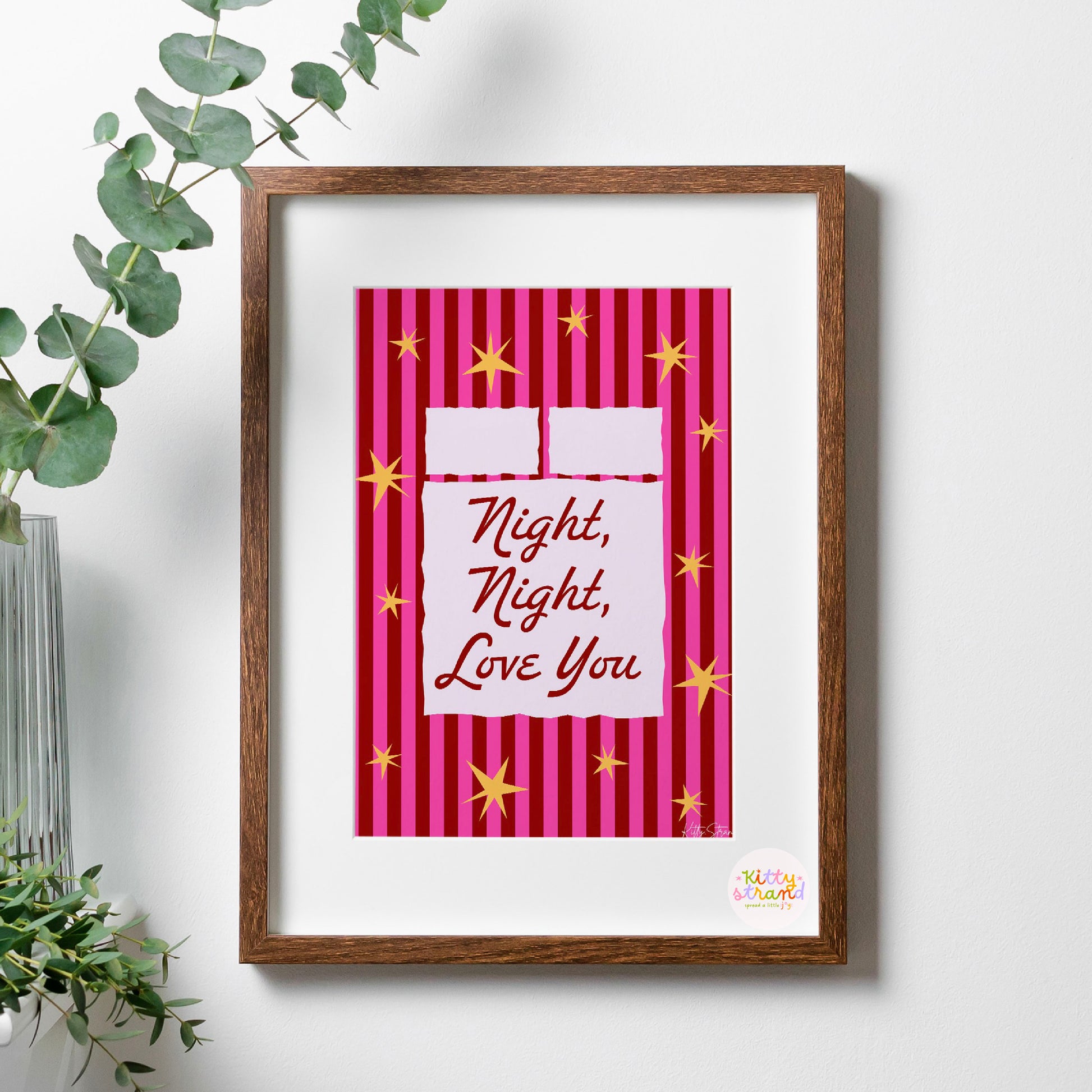 Framed artwork with 'Night, Night, Love You' text on a pink striped background, placed on a white surface with a plant.