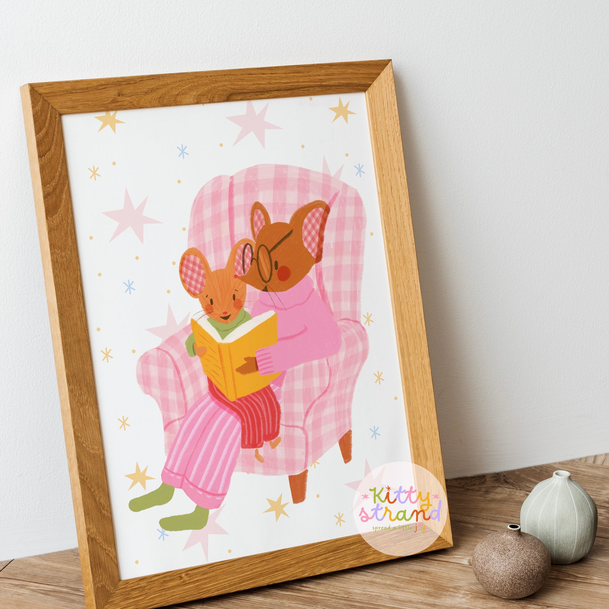 wall art with an illustration of two mice reading a book in a checkered chair with a pink background. Children's book inspired wall decor