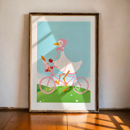 Framed artwork of a cartoon duck riding a pink bicycle with a basket on a light blue background.