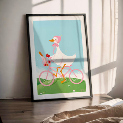 Framed artwork of a cartoon duck riding a pink bicycle indoors.