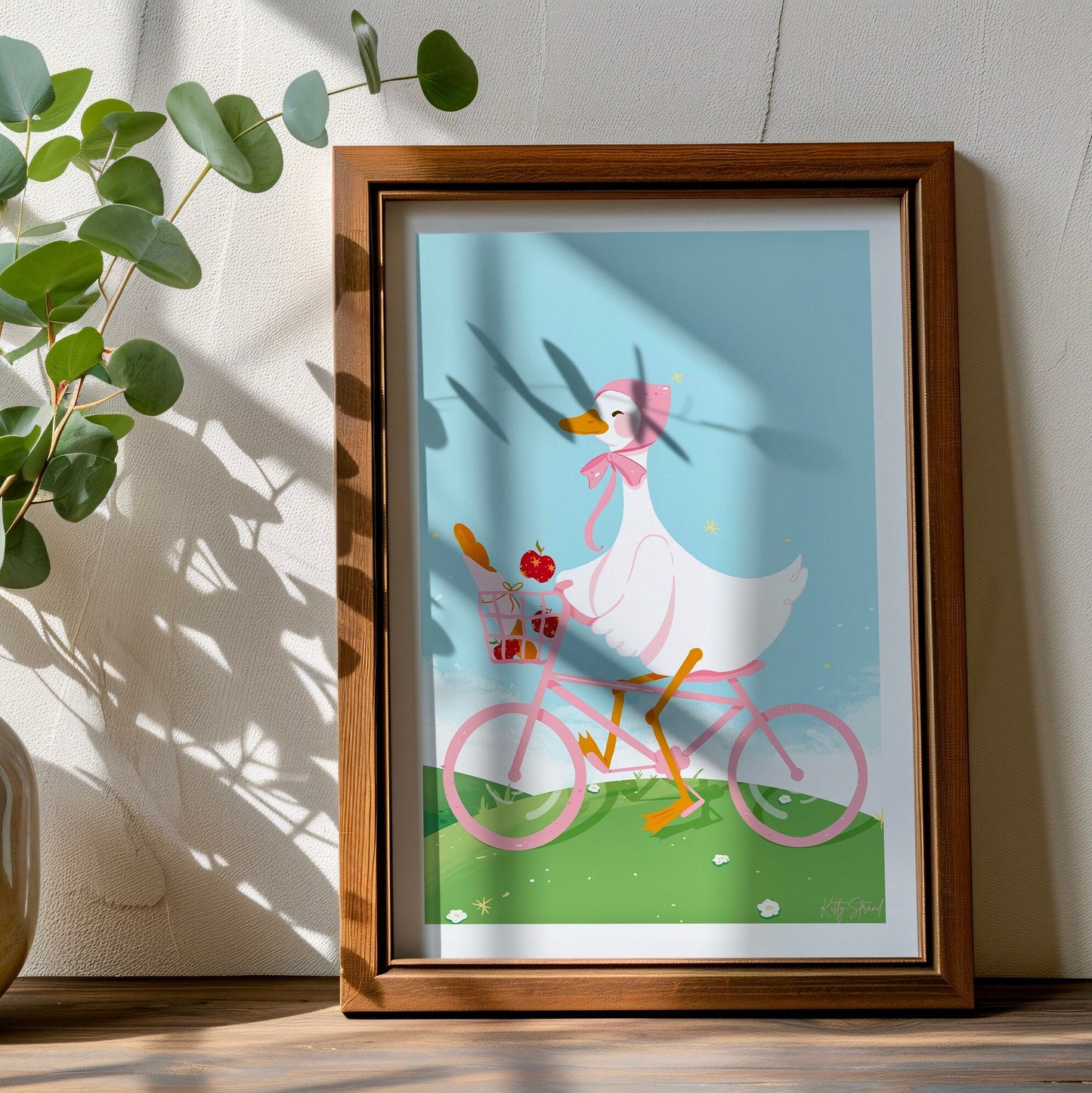 Framed illustration of a duck riding a pink bicycle on a wall.