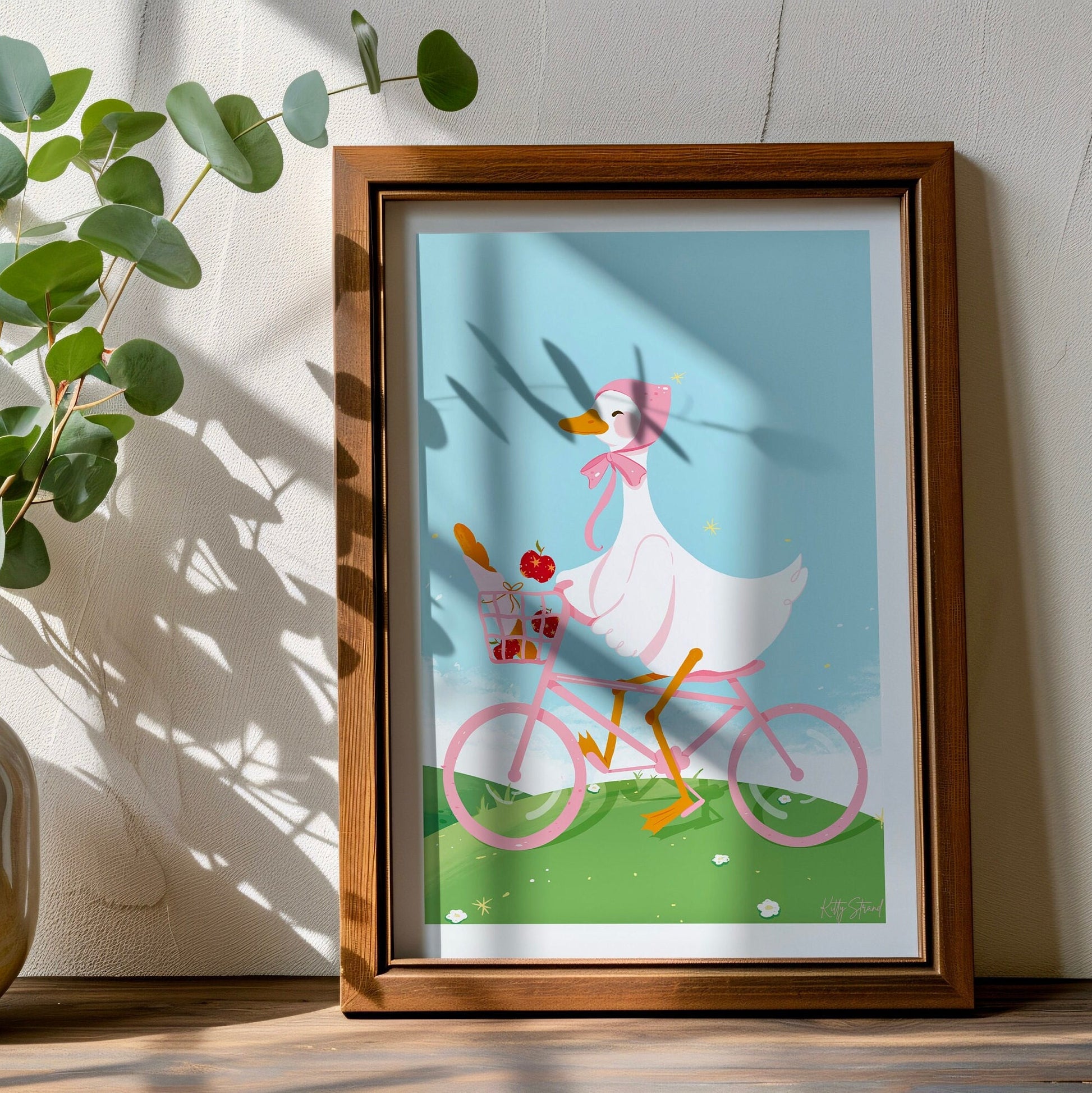 Framed illustration of a duck riding a pink bicycle on a wall.