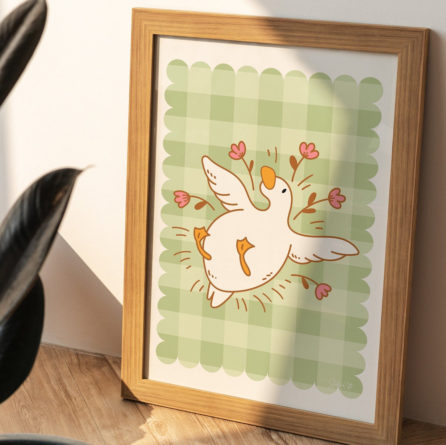 gingham wall art with an illustration of a duck / goose laying surrounded by flowers 